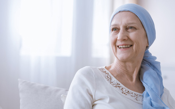 Happy woman with cancer in blue headscarf smiling with hope